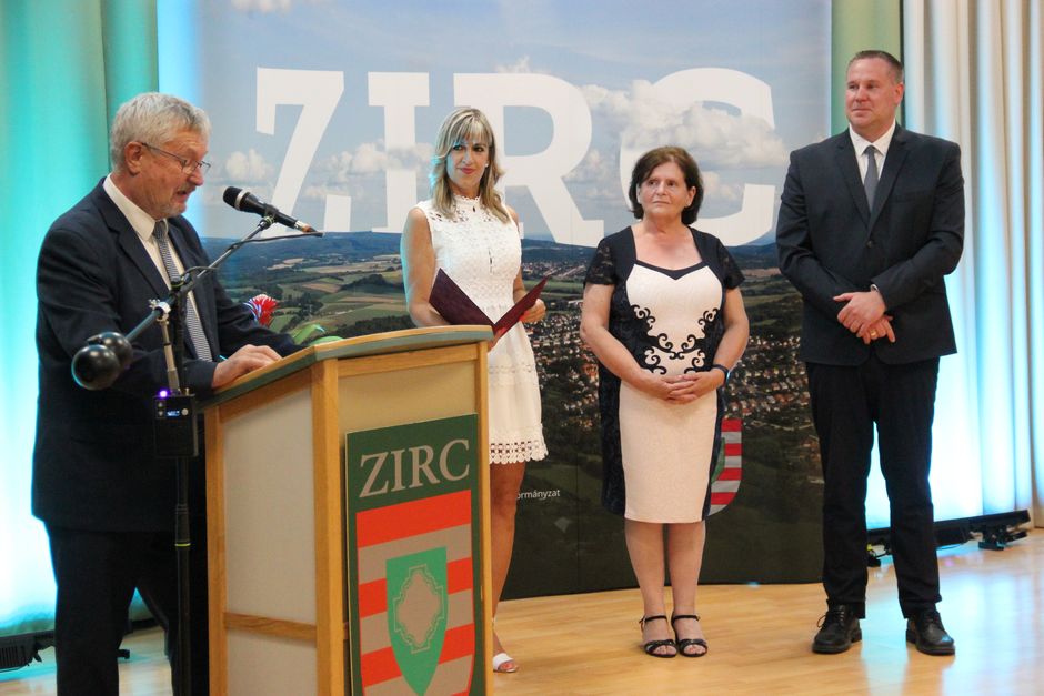 Mészárosné Gelesz Edina hallgatja a Burján István János igazgató által ismertetett méltatását a kitüntetést átadók körében